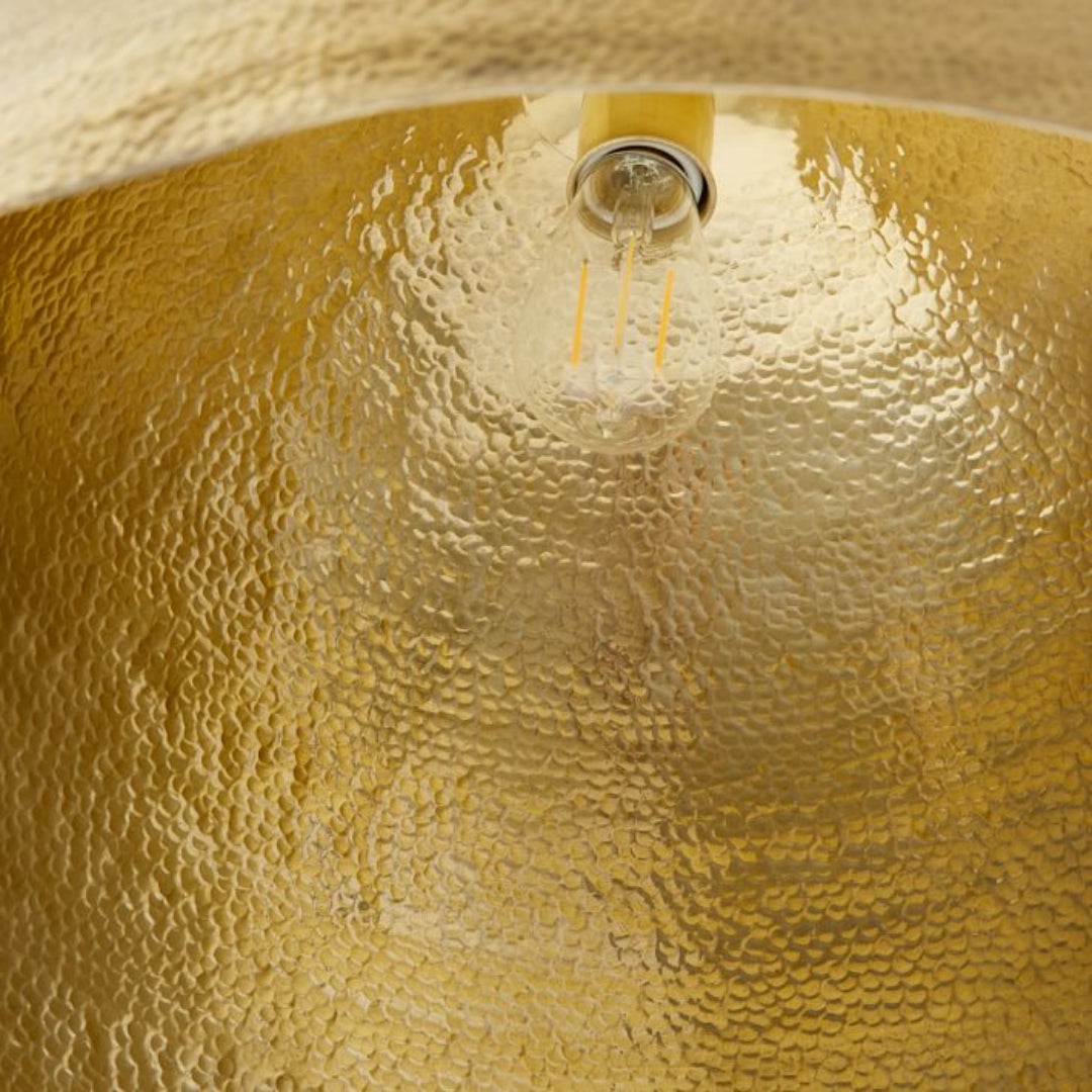Close-up of the handcrafted hammered texture on a gold brass dome lampshade.
