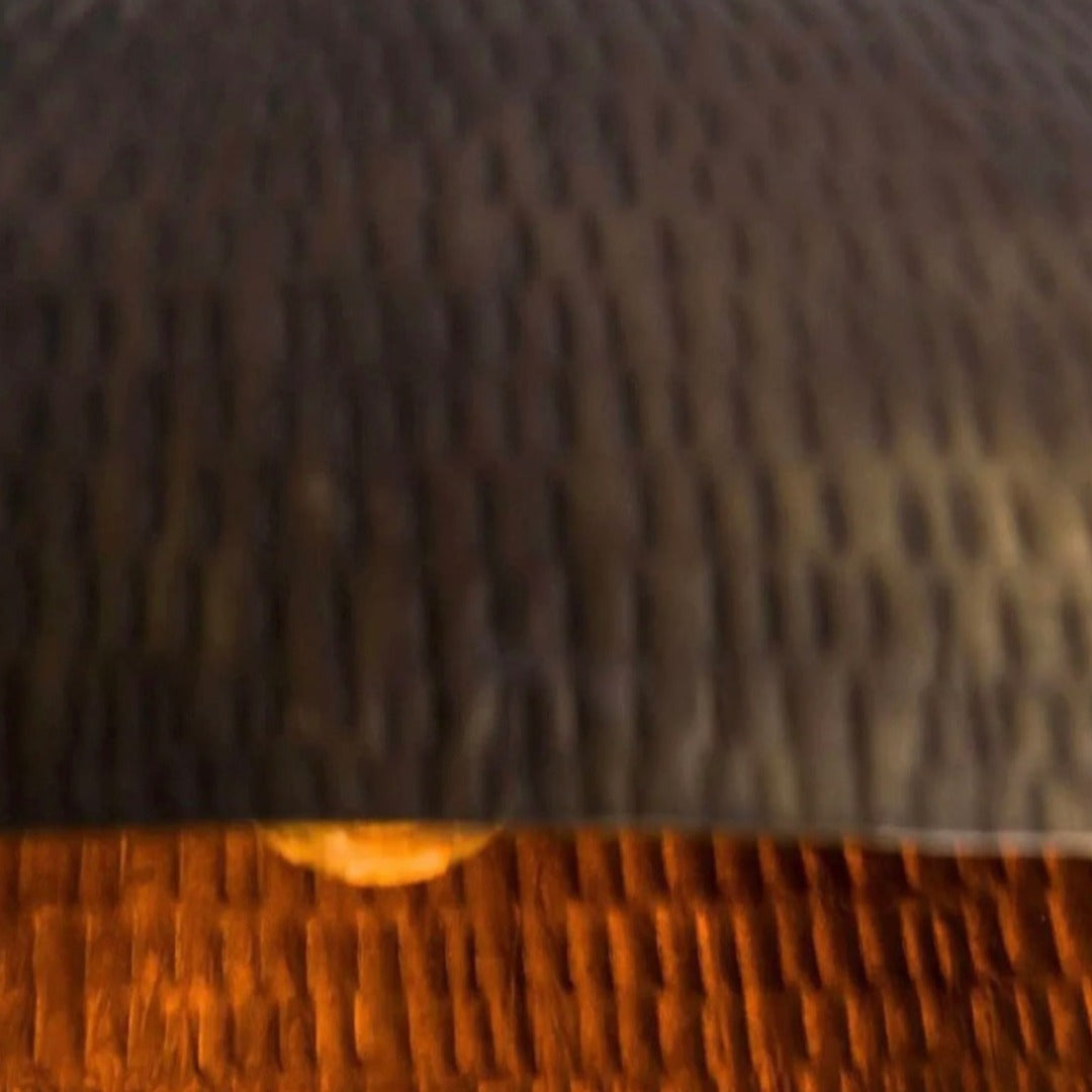 Close-up of the handcrafted hammered texture on a traditional Moroccan brass dome ceiling lamp.