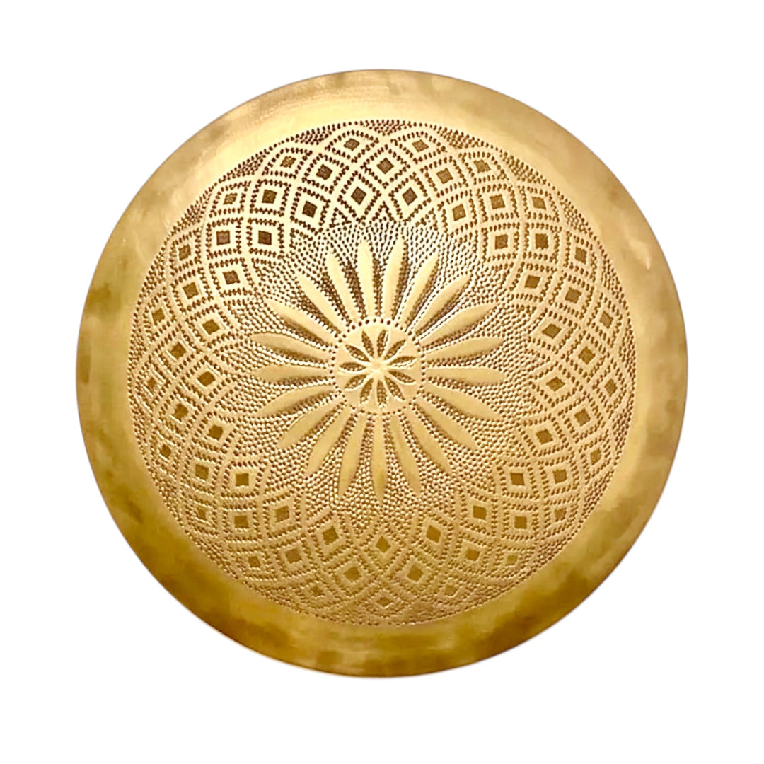 A clean isolated studio shot of a round handcrafted Moroccan brass flush mount ceiling light fixture in a polished gold finish with detailed traditional arabesque engravings.
