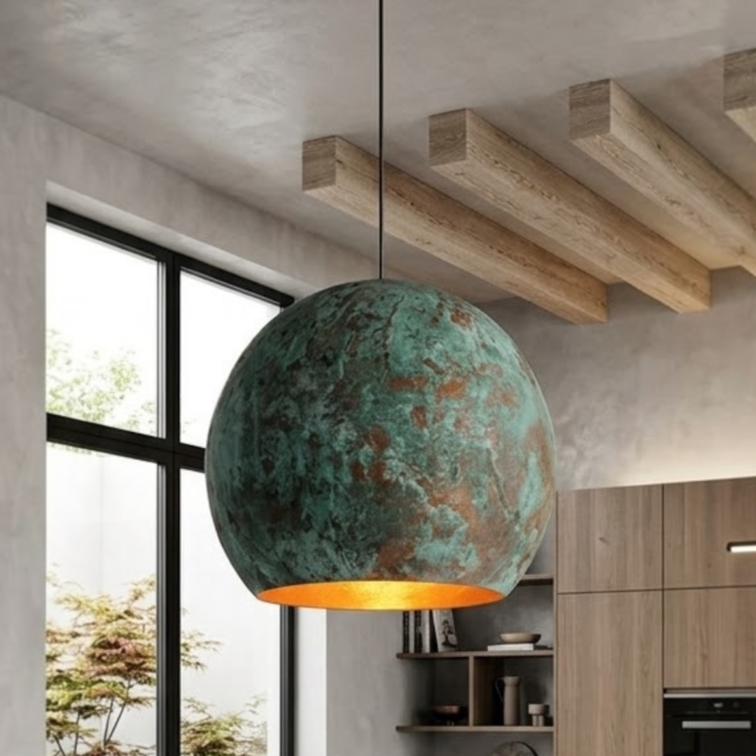 Close-up of a handmade rustic green patina copper dome pendant light with warm brass interior hanging in a modern living space