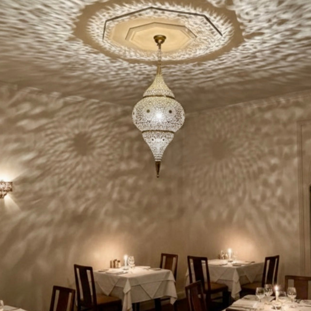 Close-up of the intricate handmade engravings and perforation on a traditional Moroccan brass ceiling fixture.