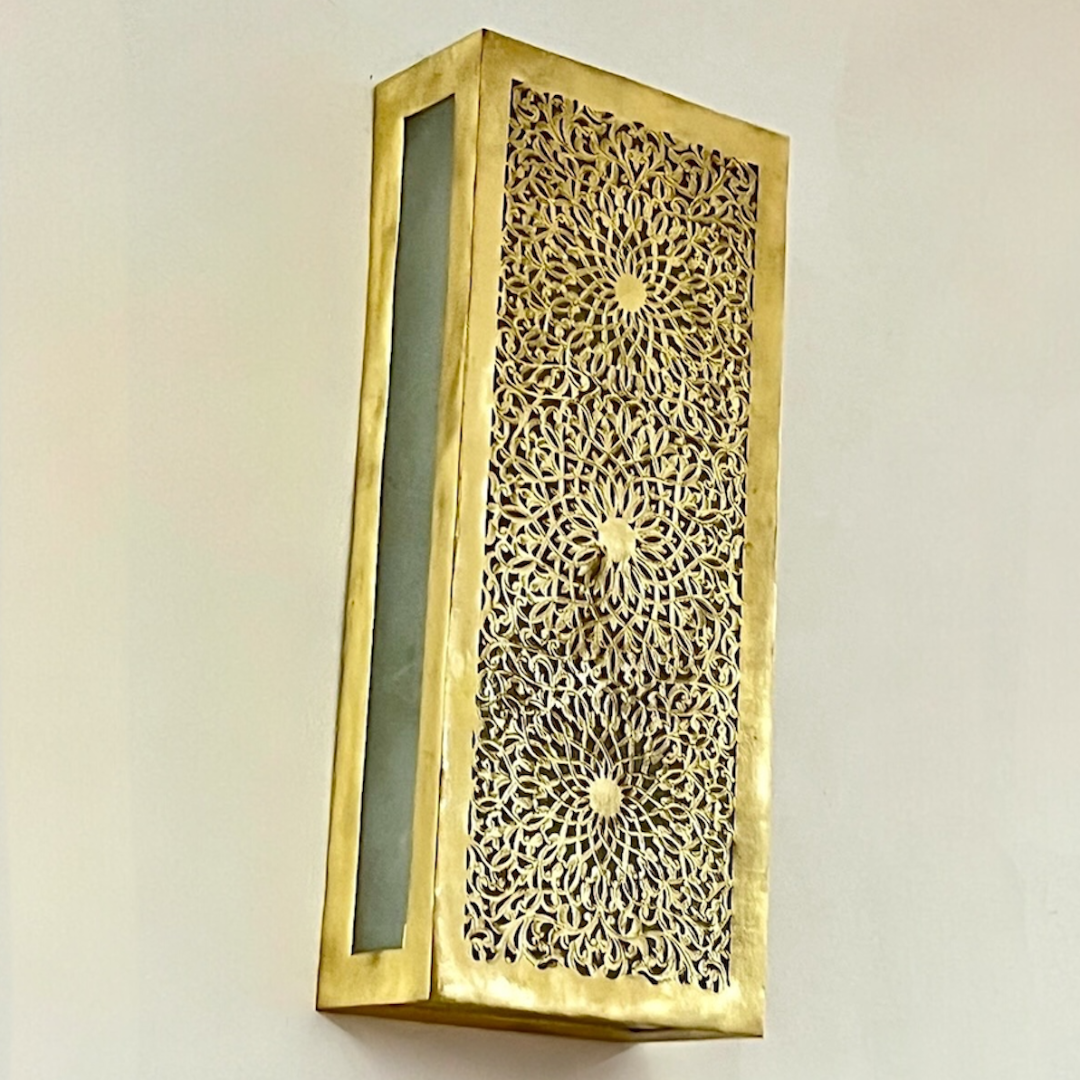 Close-up angled shot of a handmade brass wall light fixture showcasing the gold metallic finish and traditional Moroccan craftsmanship.