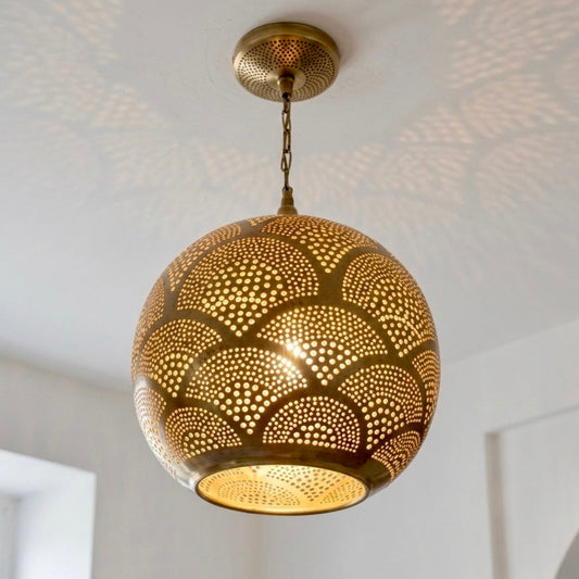 Close-up of a handmade Moroccan brass pendant light featuring intricate hand-drilled perforations in a traditional scalloped design against a white ceiling.