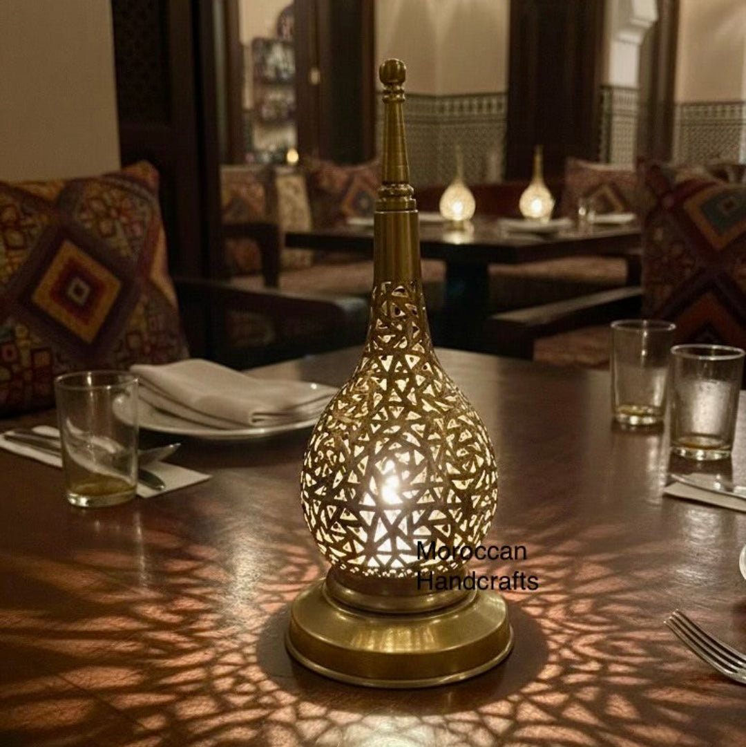 Handmade Moroccan brass lamp with intricate hand-engraved patterns on a dining table.