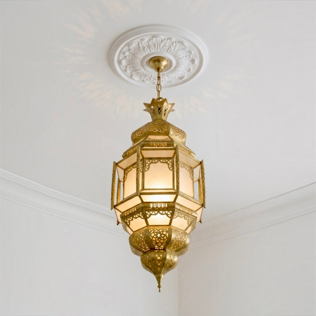  ⁠Illuminated Moroccan brass pendant lamp with frosted glass panels hanging from a decorative ceiling medallion⁠