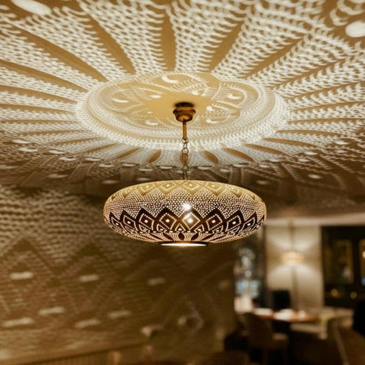 Handmade Moroccan brass pendant light casting intricate shadow patterns on the ceiling.