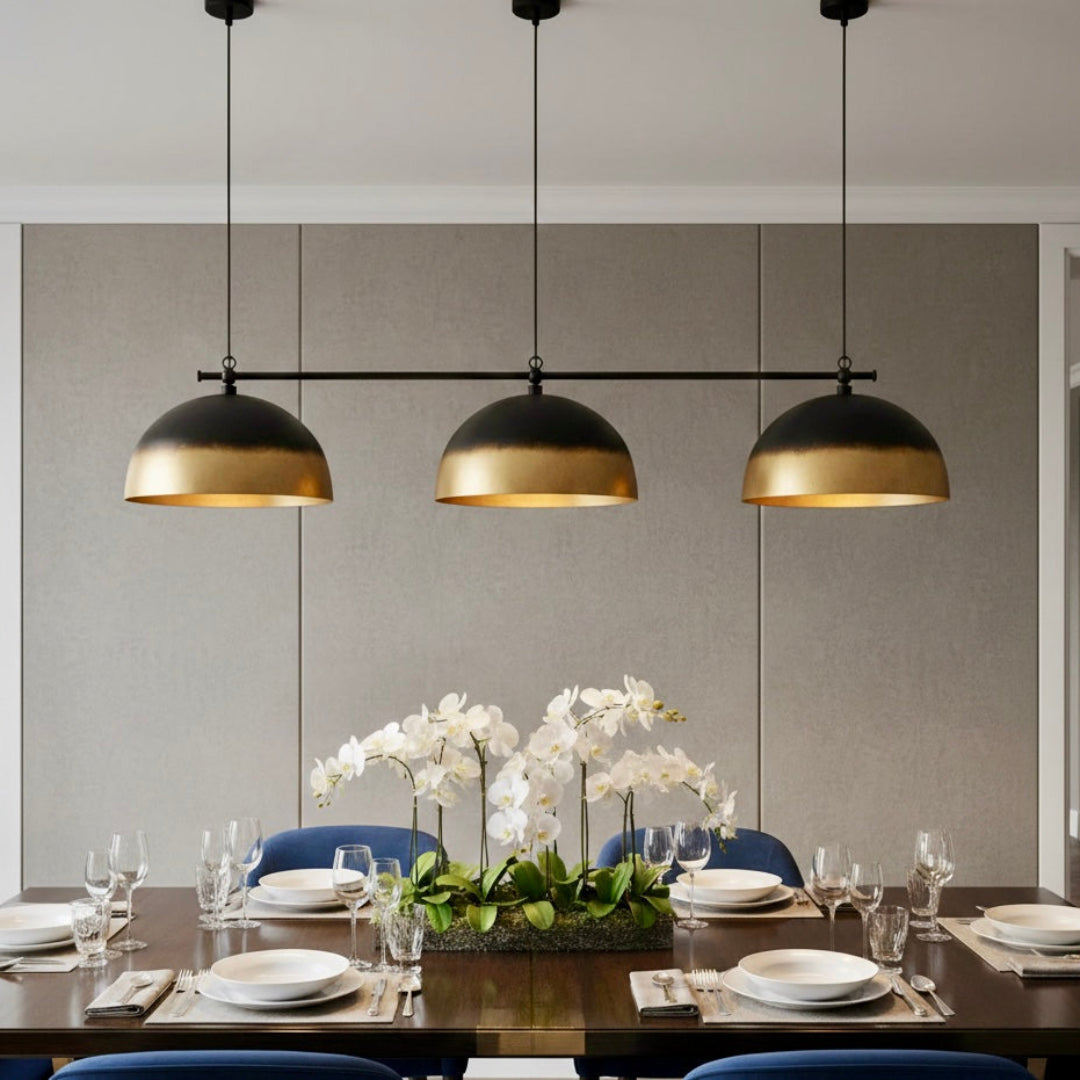 Hand-hammered Moroccan brass dome pendant light hanging over a formal dining table with green velvet chairs.