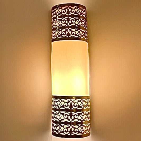 Front view of a cylindrical handmade Moroccan brass wall lamp featuring traditional geometric fretwork and a warm glowing center.