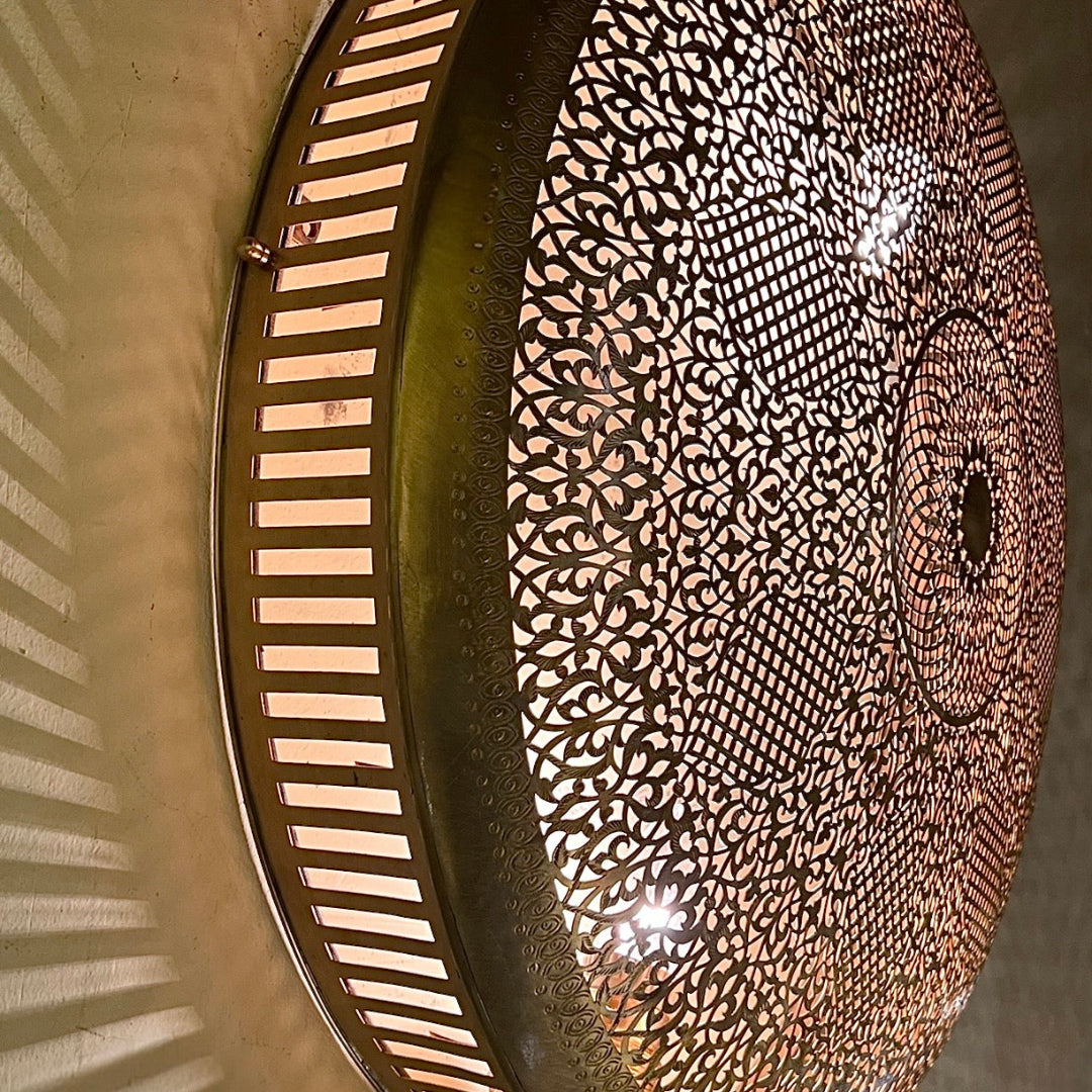 Close-up top view of a handcrafted Moroccan brass wall light with intricate geometric cutouts.