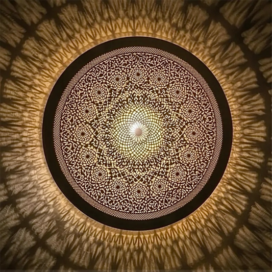 Close-up details of a handmade Moroccan flush mount brass lamp showing intricate geometric filigree patterns and warm shadows.