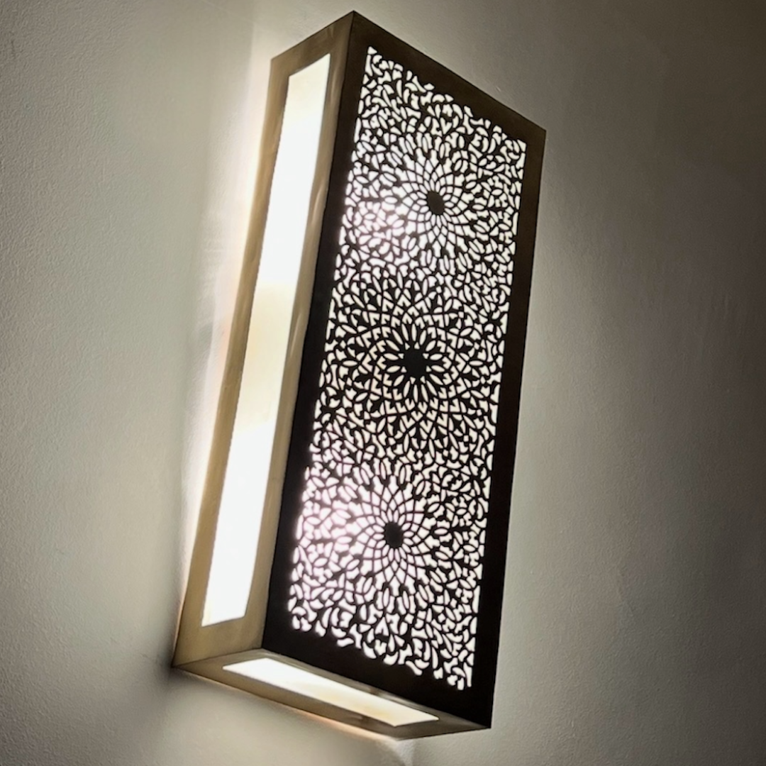 Side perspective of an illuminated Moroccan brass sconce showing the warm glow and artisan metalwork shadows.