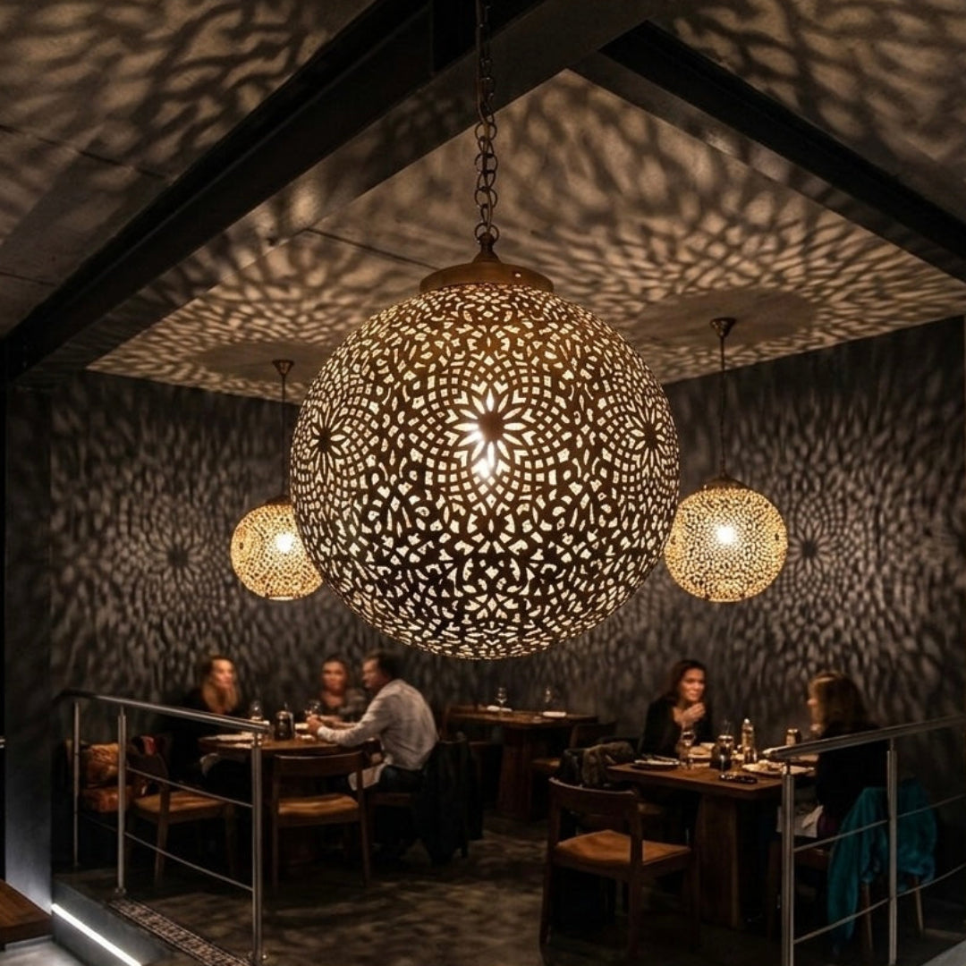 Multiple Moroccan brass pendant lamps installed in a dark, modern industrial restaurant creating a luxury shadow effect.