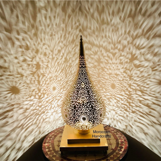 Full view of a tall, hand-pierced Moroccan filigree table lamp illuminating a warm living room setting.