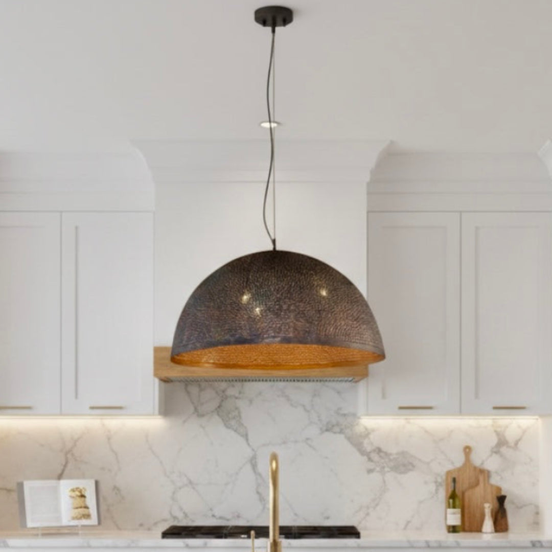  A single oversized Moroccan handmade brass dome light hanging in a luxury white kitchen with a navy blue island.