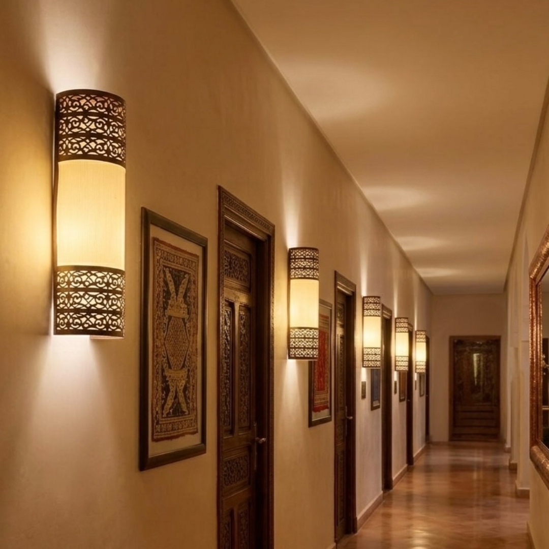 A row of tall Moroccan brass wall lamps lighting up a luxury Riad hotel hallway, highlighting traditional North African interior design.