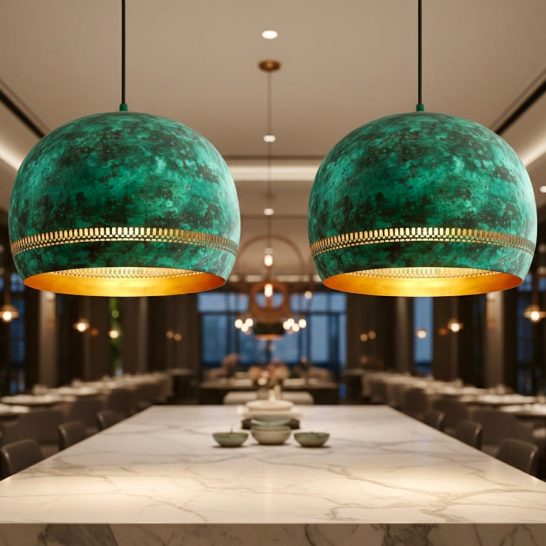 Two large verdigris green brass dome pendant lights with perforated gold detailing in a luxury dining hall.