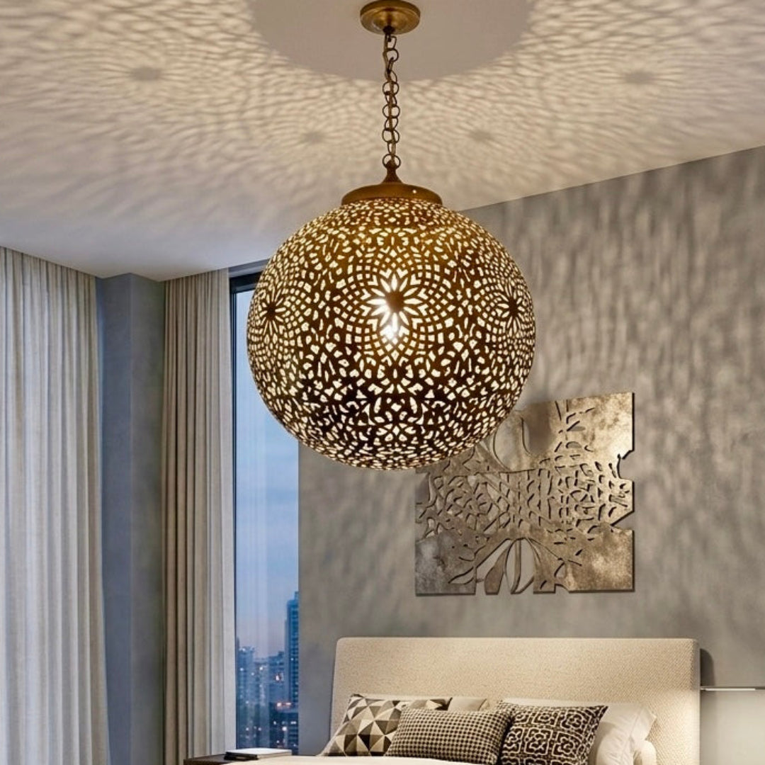 Large gold Moroccan brass lamp in a bright contemporary bedroom with floor-to-ceiling windows and minimalist furniture.