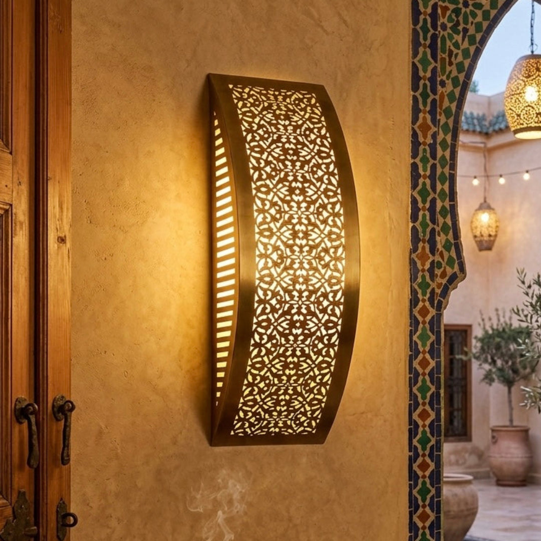 Traditional Moroccan interior featuring a brass wall sconce mounted on a textured wall near a carved wooden door.