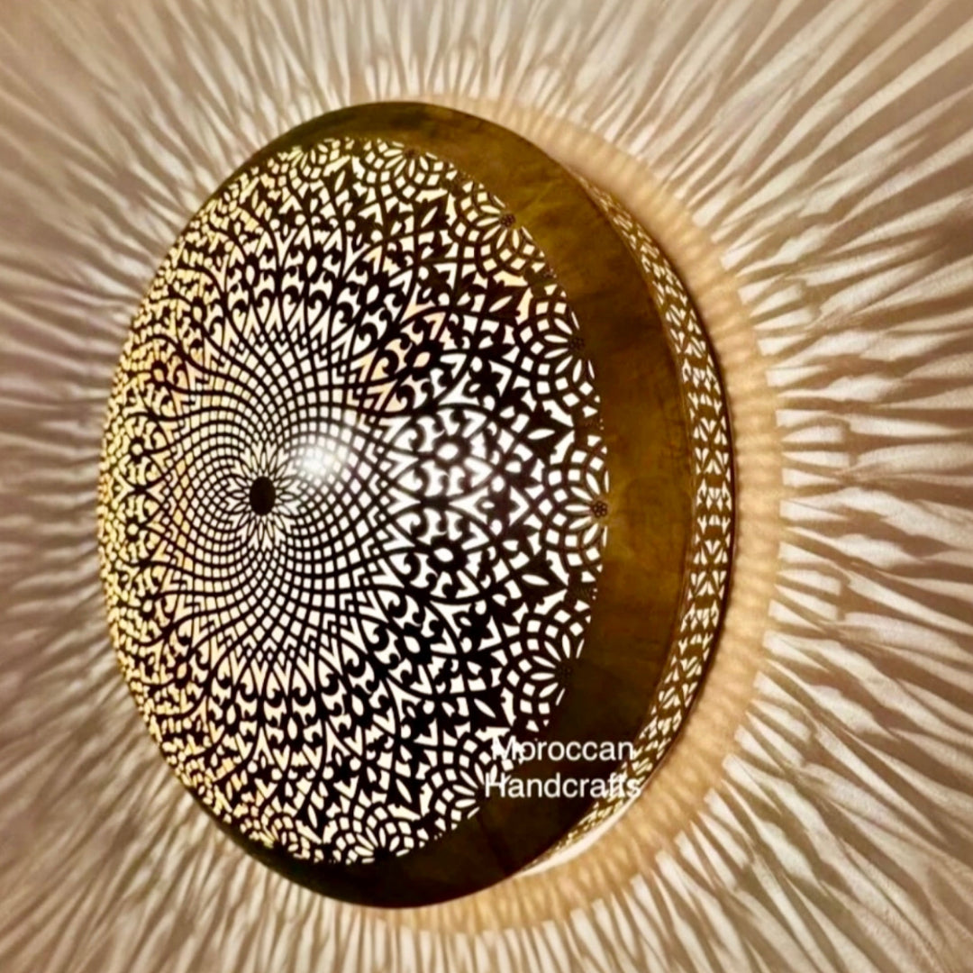 Side angle view of an illuminated round Moroccan brass flush mount light casting dynamic geometric ray shadows across the wall and ceiling, perfect for modern luxury home decor.