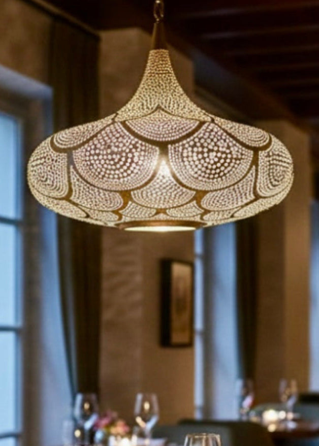 Exquisite brass Moroccan filigree pendant light hanging above a dining table in a luxury restaurant.