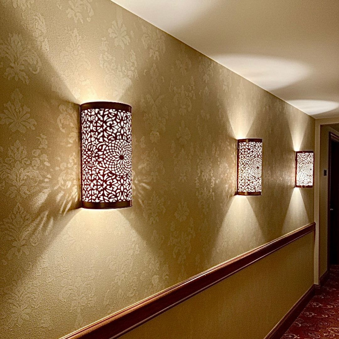  A series of elegant Moroccan-style brass wall sconces lining a warm-toned hallway, creating a cozy and luxurious atmosphere.