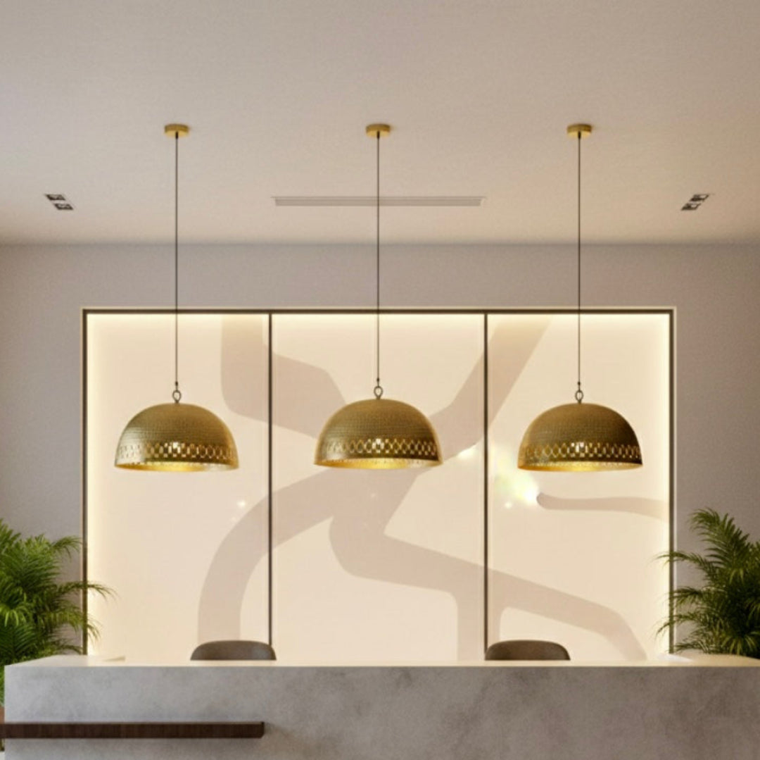  Three minimalist Moroccan brass pendant lamps installed in a luxury office reception area with a neutral stone desk and warm backlight.