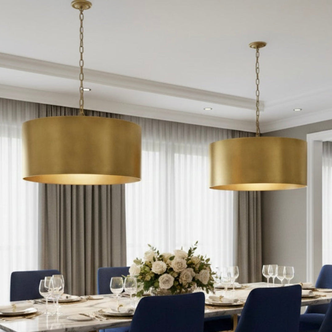 Multiple large brass drum pendant lights hanging in a luxury modern restaurant setting with city views.