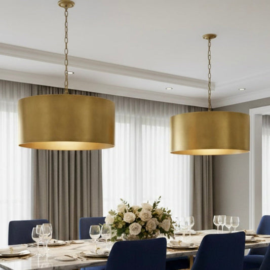 Multiple large brass drum pendant lights hanging in a luxury modern restaurant setting with city views.