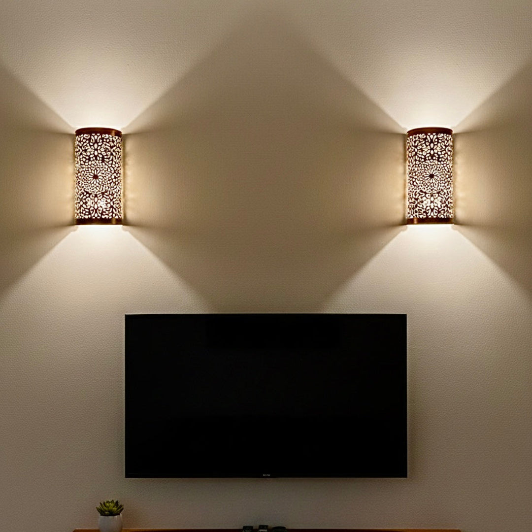 A modern living room wall featuring two Moroccan brass sconces installed on either side of a television, providing ambient accent lighting.