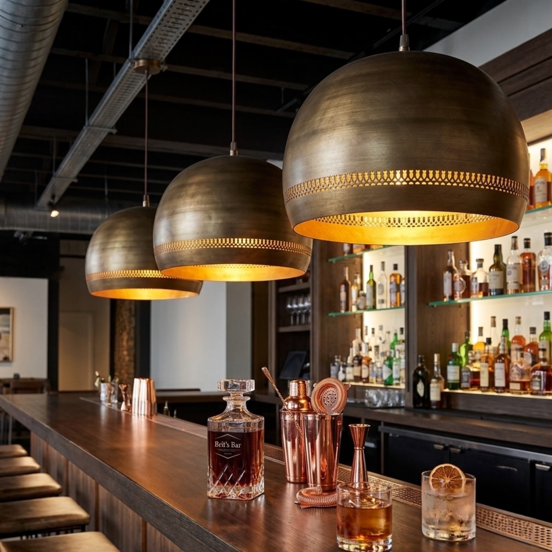 Three brass dome pendant lights featuring delicate perforated details illuminated above a stylish commercial bar counter
