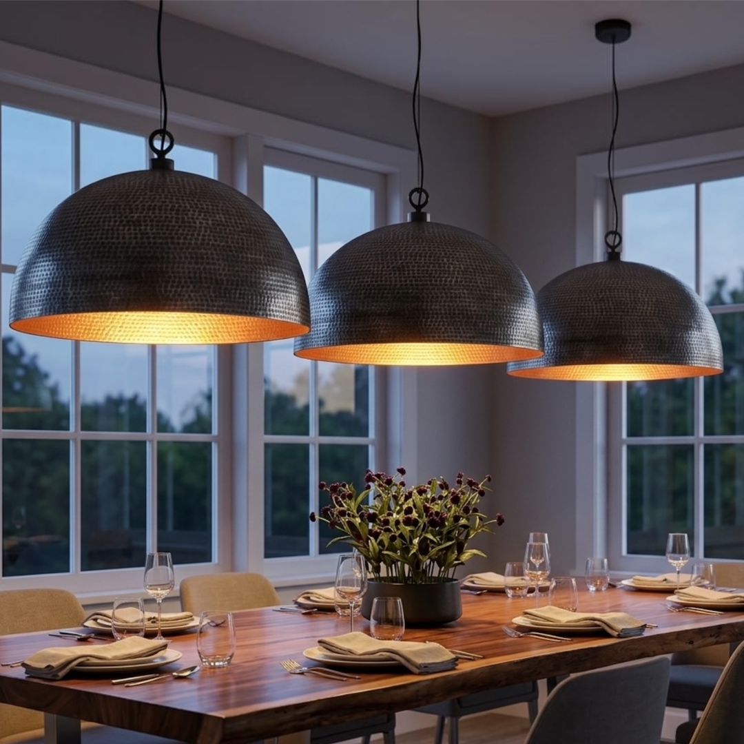 Trio of hammered dark brass Moroccan dome pendant lights with warm gold interior illuminating a modern wooden dining table