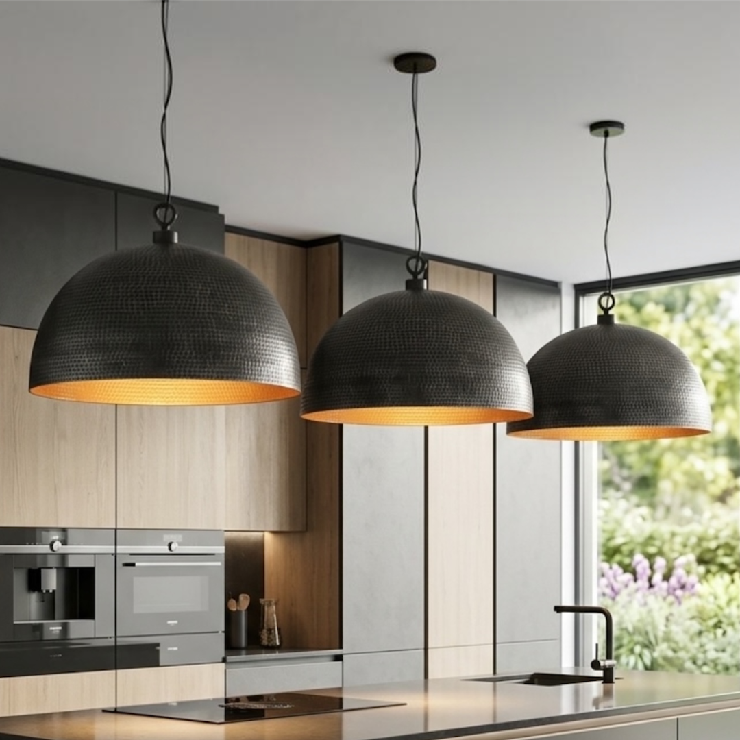 Three handcrafted Moroccan brass dome pendant lights hanging above a modern black marble kitchen island