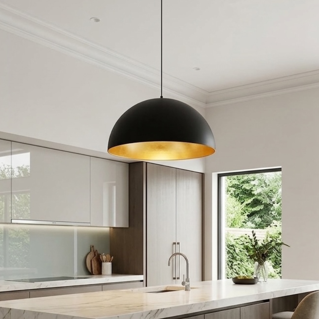 Handmade matte black Moroccan dome pendant light with gold brass interior over a marble kitchen island