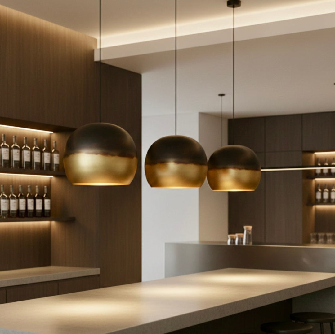 Three hand-hammered Moroccan brass dome lights illuminating a modern home bar area with dark wood shelving.