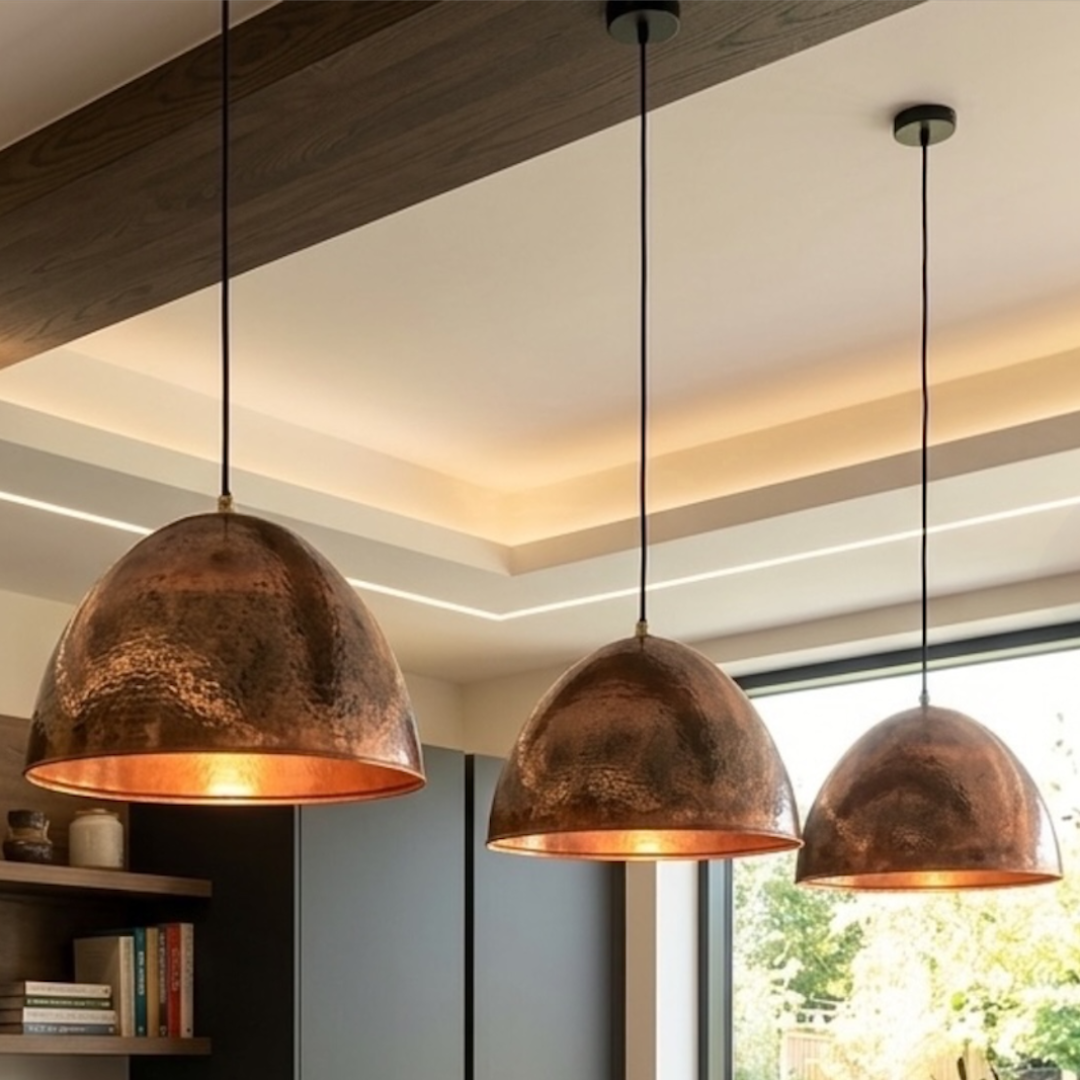  Trio of rustic hammered copper dome pendant lamps illuminating a modern luxury kitchen island with dark cabinetry