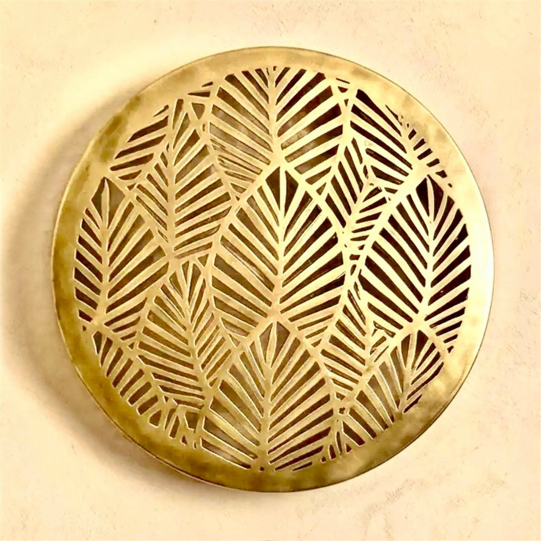 Unlit round Moroccan brass wall lamp fixture showcasing the detailed handmade palm leaf fretwork against a neutral plaster wall background.