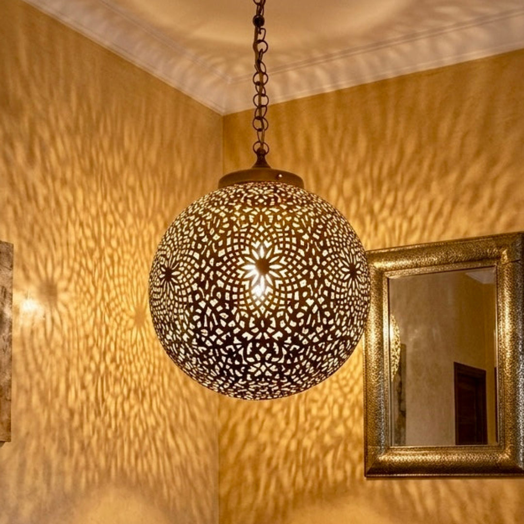 Moroccan brass ceiling lamp casting ornate shadows in a cozy boho living room with colorful cushions and a carved wooden table.