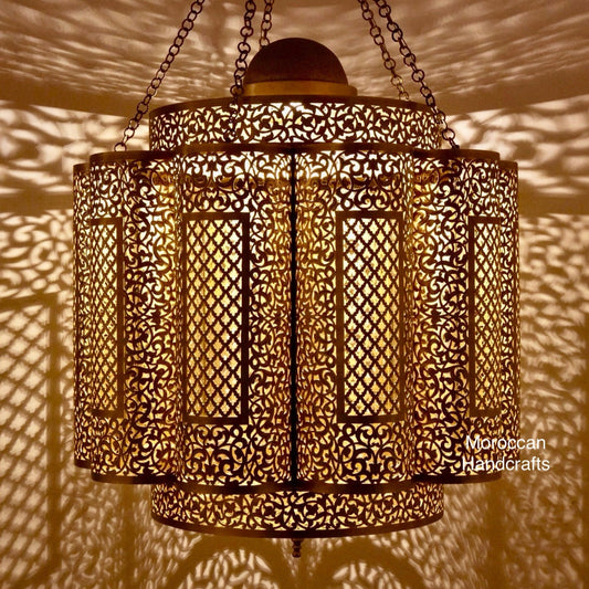 Handcrafted Moroccan brass chandelier with intricate filigree metalwork and soft, patterned shadow casting on the wall.
