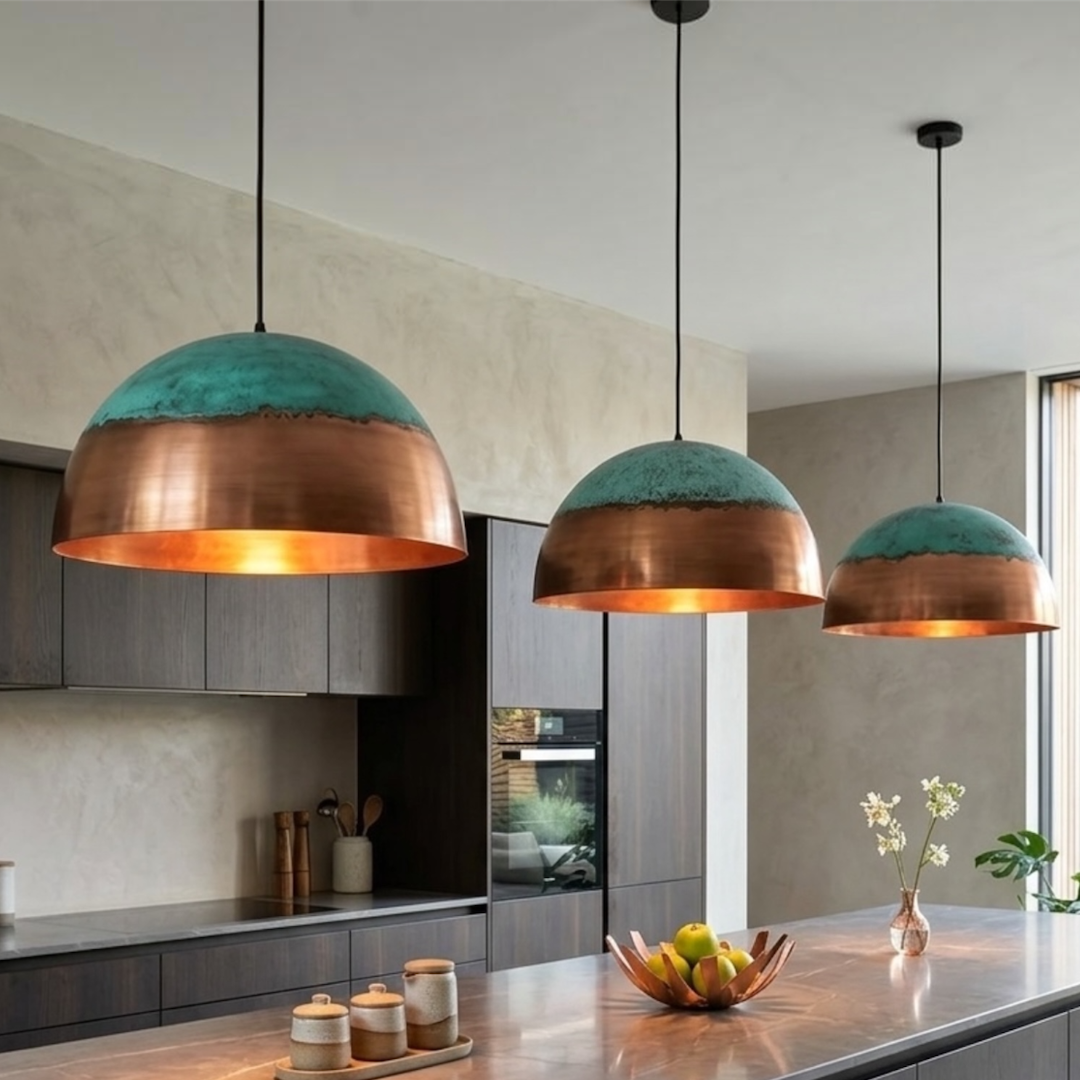 Trio of handcrafted modern brass dome pendant lamps with verdigris patina detailing over a dark wood kitchen island