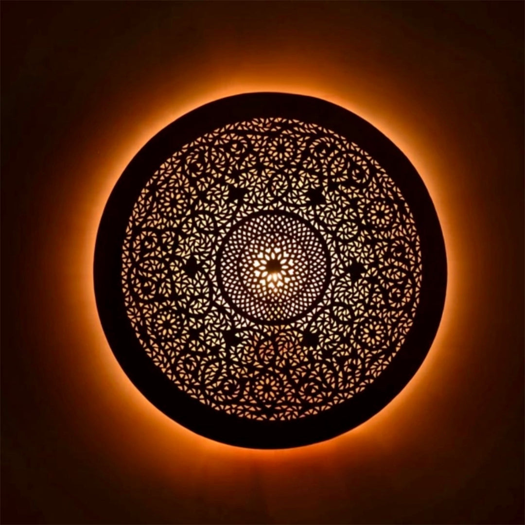 Handmade Moroccan brass flush mount ceiling light glowing with a warm orange ambiance, showing intricate geometric hand-pierced patterns.