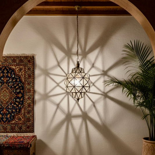 Handcrafted Moroccan brass and glass pendant lamp casting geometric shadows on a white wall.
