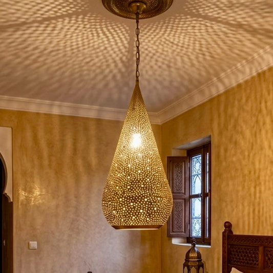 Authentic Moroccan brass ceiling light creating shadow patterns in a cozy bedroom with traditional Moorish decor.