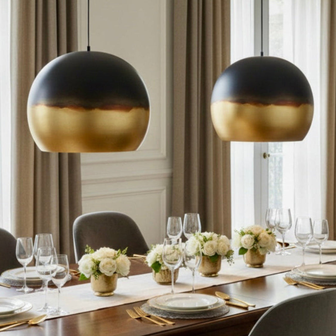 Two large Moroccan dome pendant lights in aged brass hanging above a formal wooden dining table with elegant place settings.