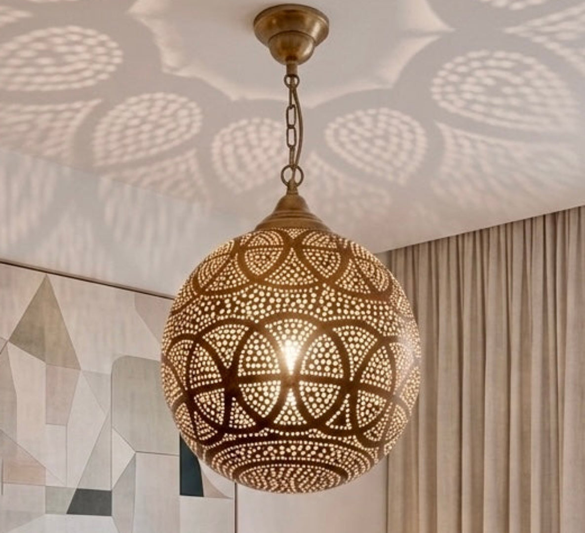 Cozy, modern bedroom interior styled with an authentic Moroccan brass pendant lamp that creates a relaxing, warm ambiance with decorative wall shadows.