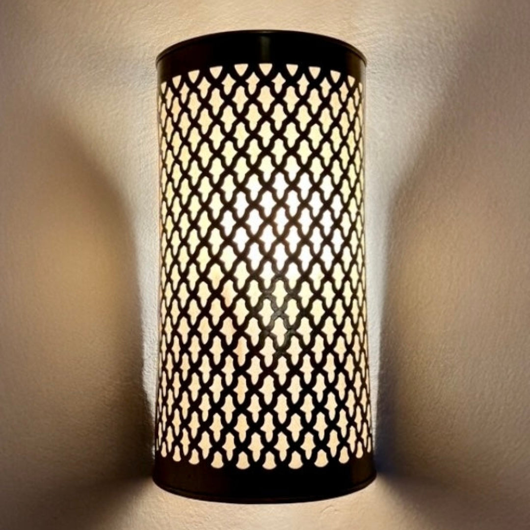 A wall-mounted Moroccan brass sconce illuminating a room with warm ambient light through ornate filigree metalwork.