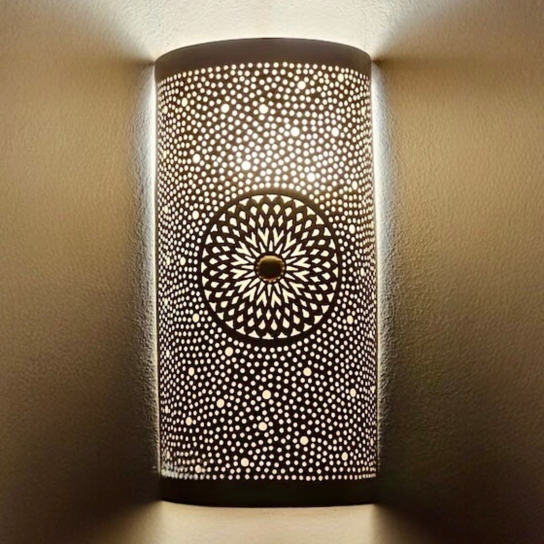  A row of cylinder-shaped Moroccan brass wall lamps casting intricate shadow patterns in a traditional warm-toned restaurant hallway.