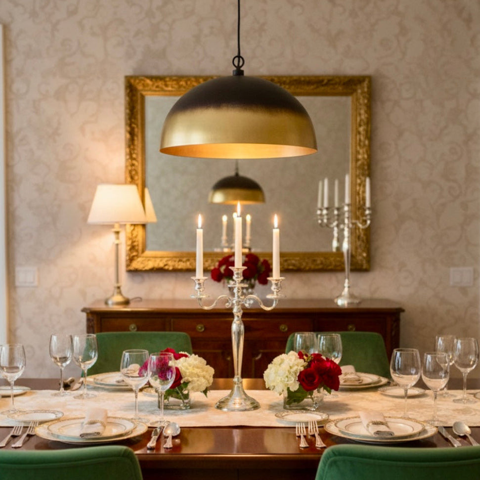 Handmade Moroccan dome lamp in brushed brass and matte black finish, hanging over a luxury dining table with green velvet chairs.