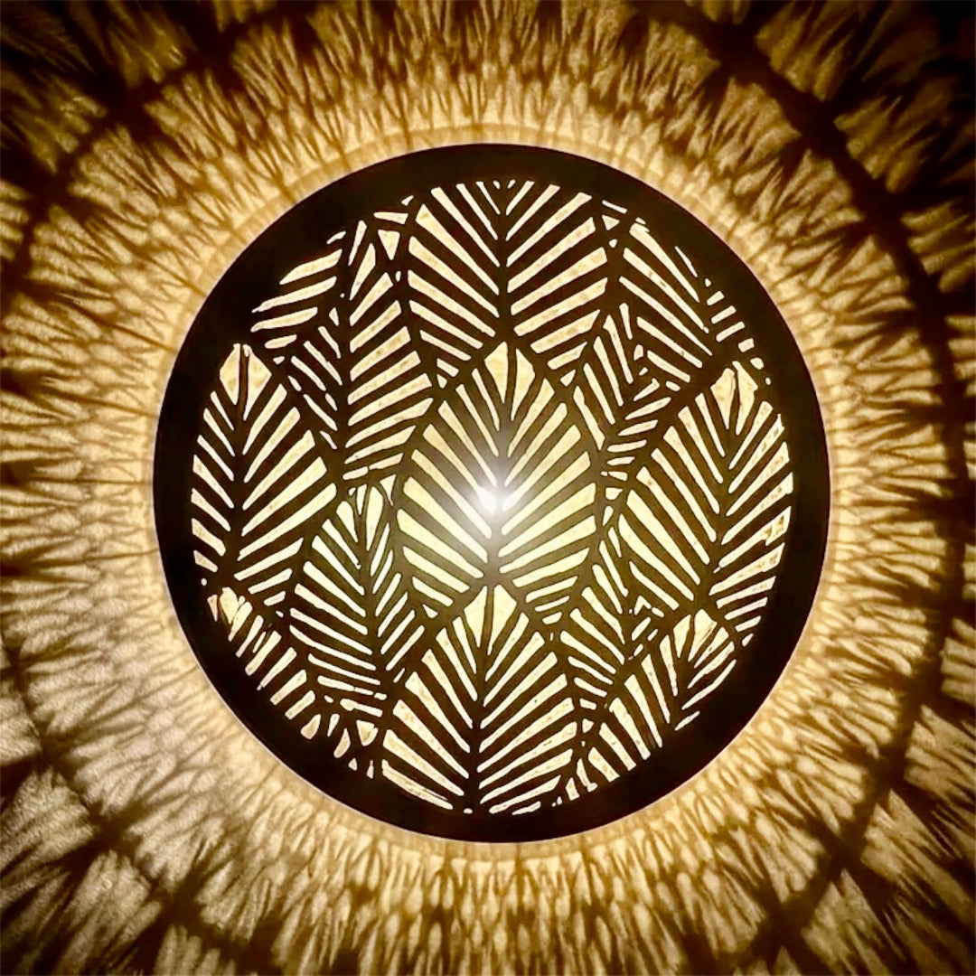 Extreme macro detail of the handcrafted side border and leaf patterns on a traditional Moroccan brass wall sconce, highlighting the artisan craftsmanship.