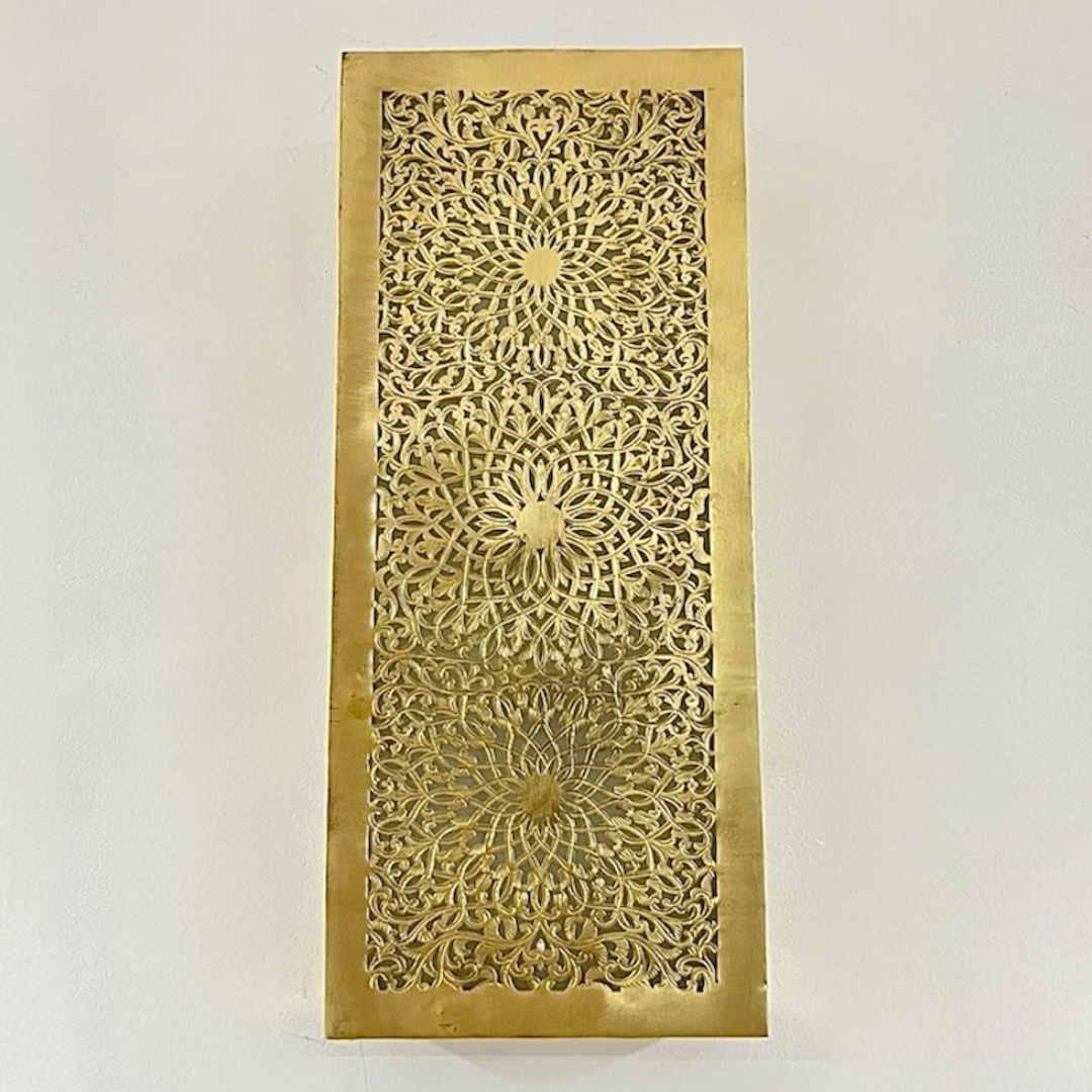 Symmetrical view of a lighted Moroccan filigree wall lamp projecting a soft ambient glow through hand-cut patterns.