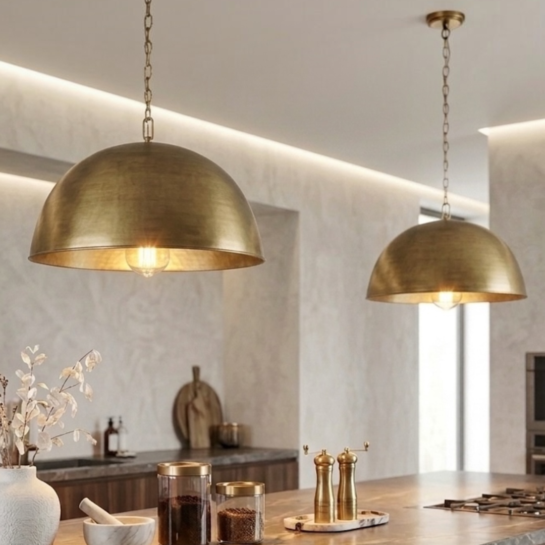 Pair of modern Moroccan handmade brass dome pendant lights hanging above a dark marble kitchen island with warm lighting